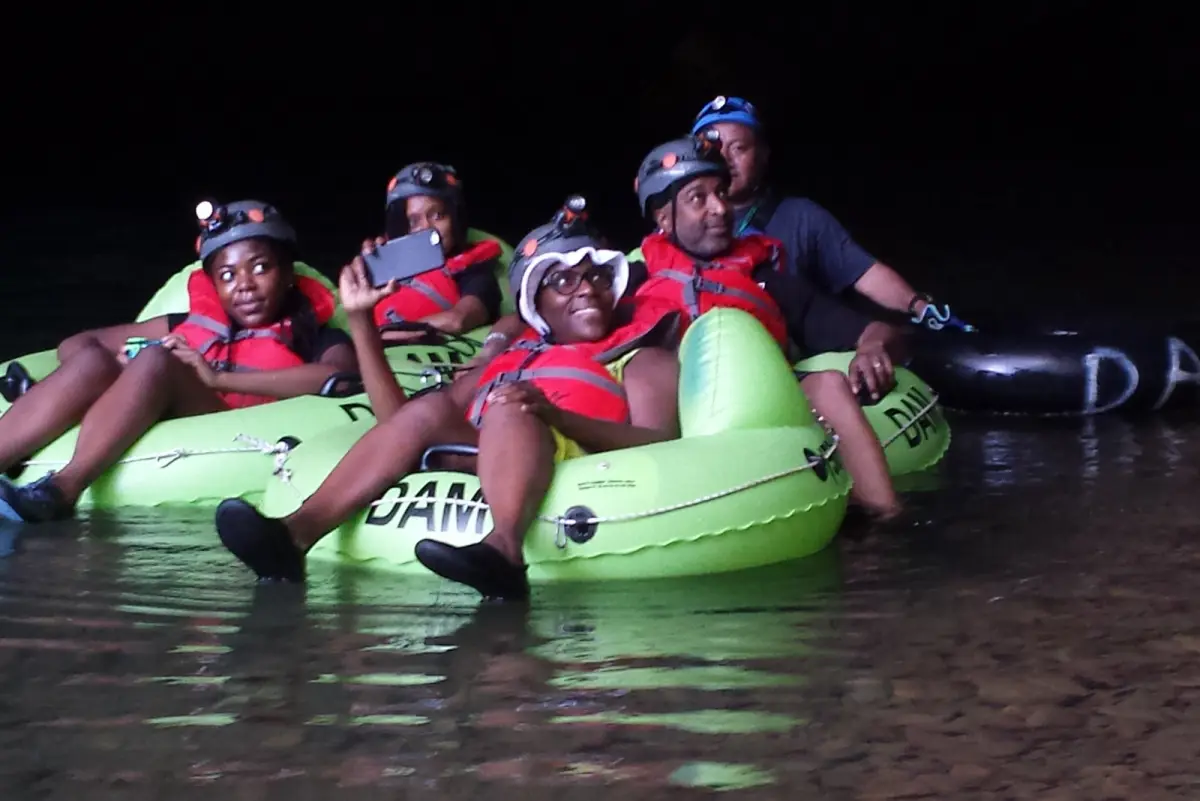 Travelers floating through a Belize cave on inner tubes
