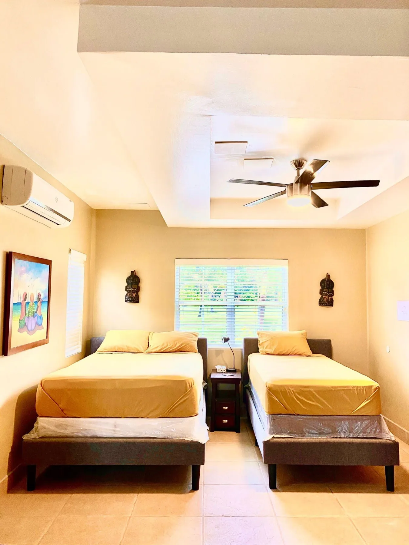 Double and twin beds beneath a ceiling fan in the Macaw Suite